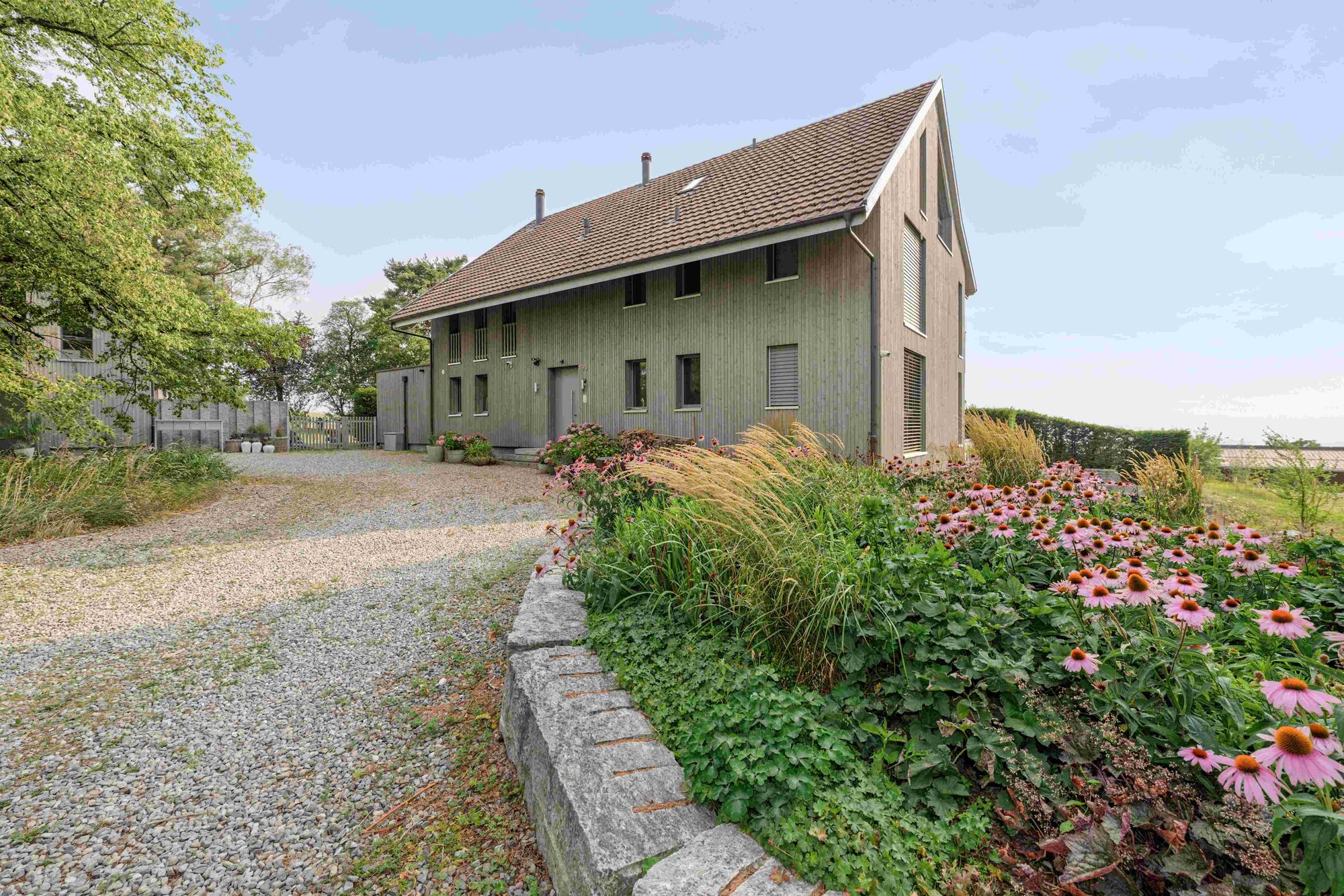 Haupthaus des Sennhof Estate mit hellem Holz, grossen Fenstern und Kiesvorplatz